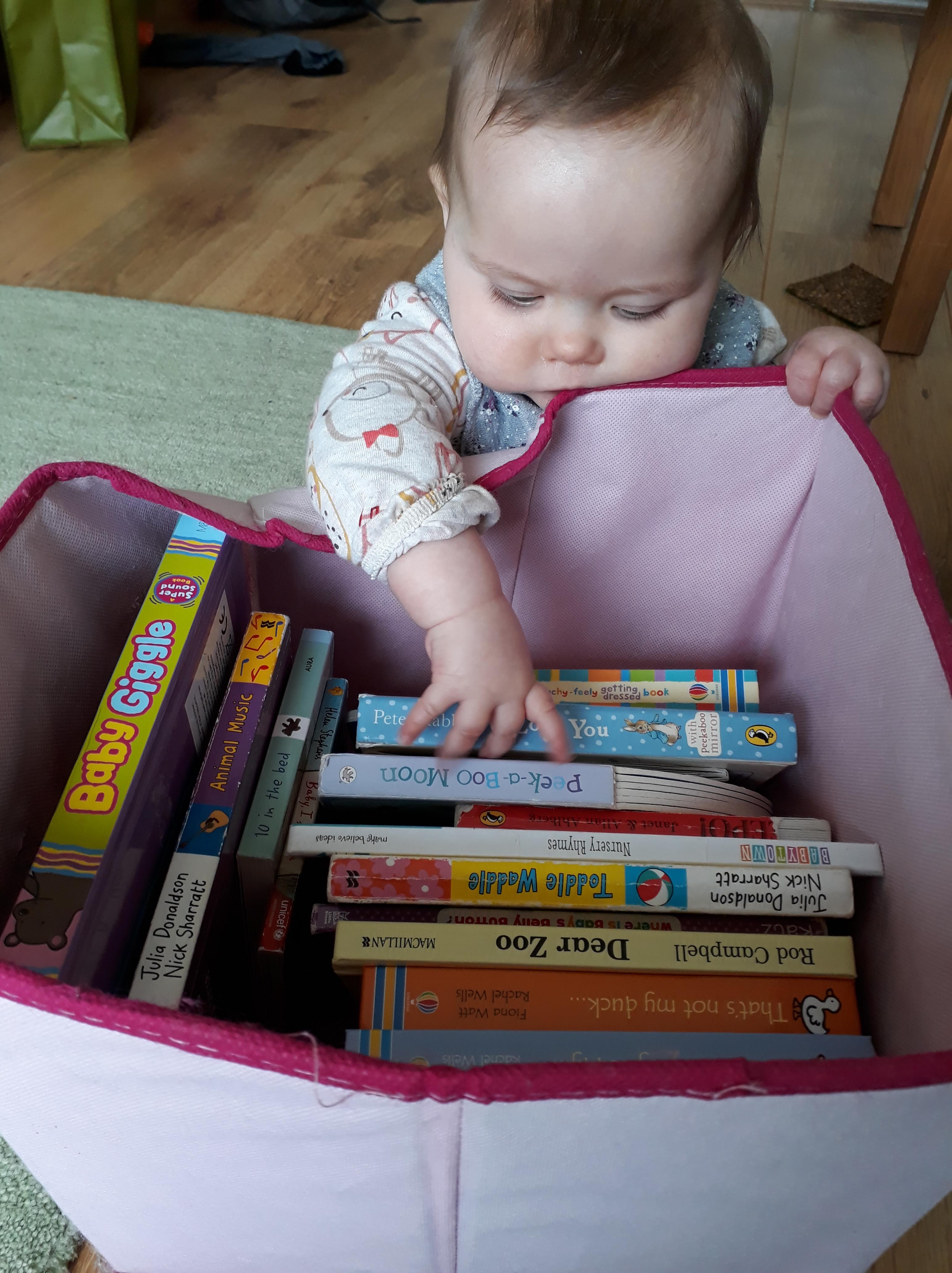 Baby reaching into a box of children's books